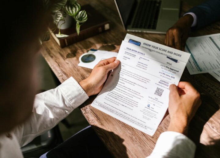 An adult man examining a financial document under natural light at a wooden desk, emphasizing finance and reading.