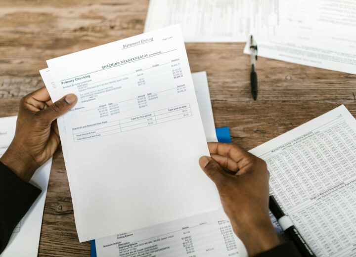 Hands holding financial papers for tax preparation and analysis.