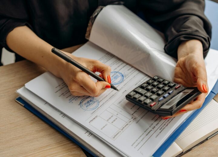 An accountant using a calculator and signing paperwork, showcasing financial analysis.